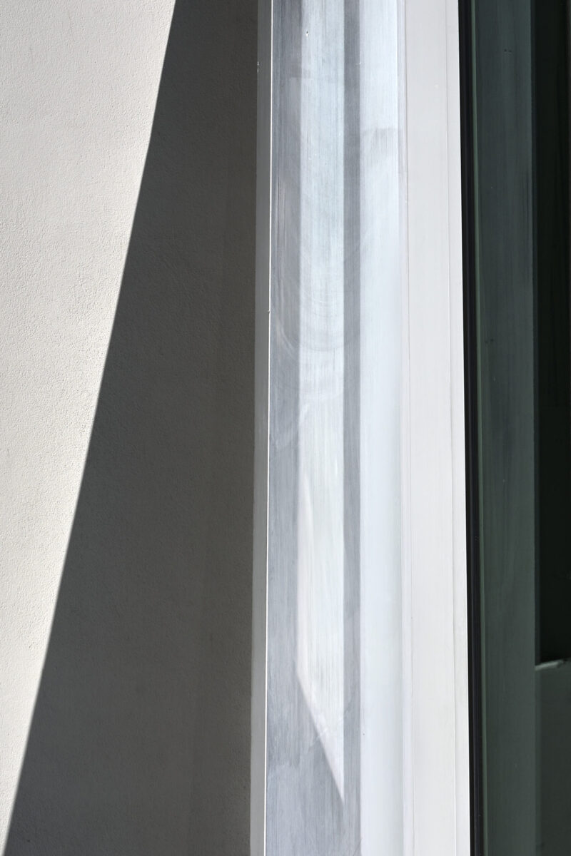 abstrakter minimalistischer Ausschnitt einer verschachtelten Hausfassade mit Schrägen und Horizontalen, Hochformat