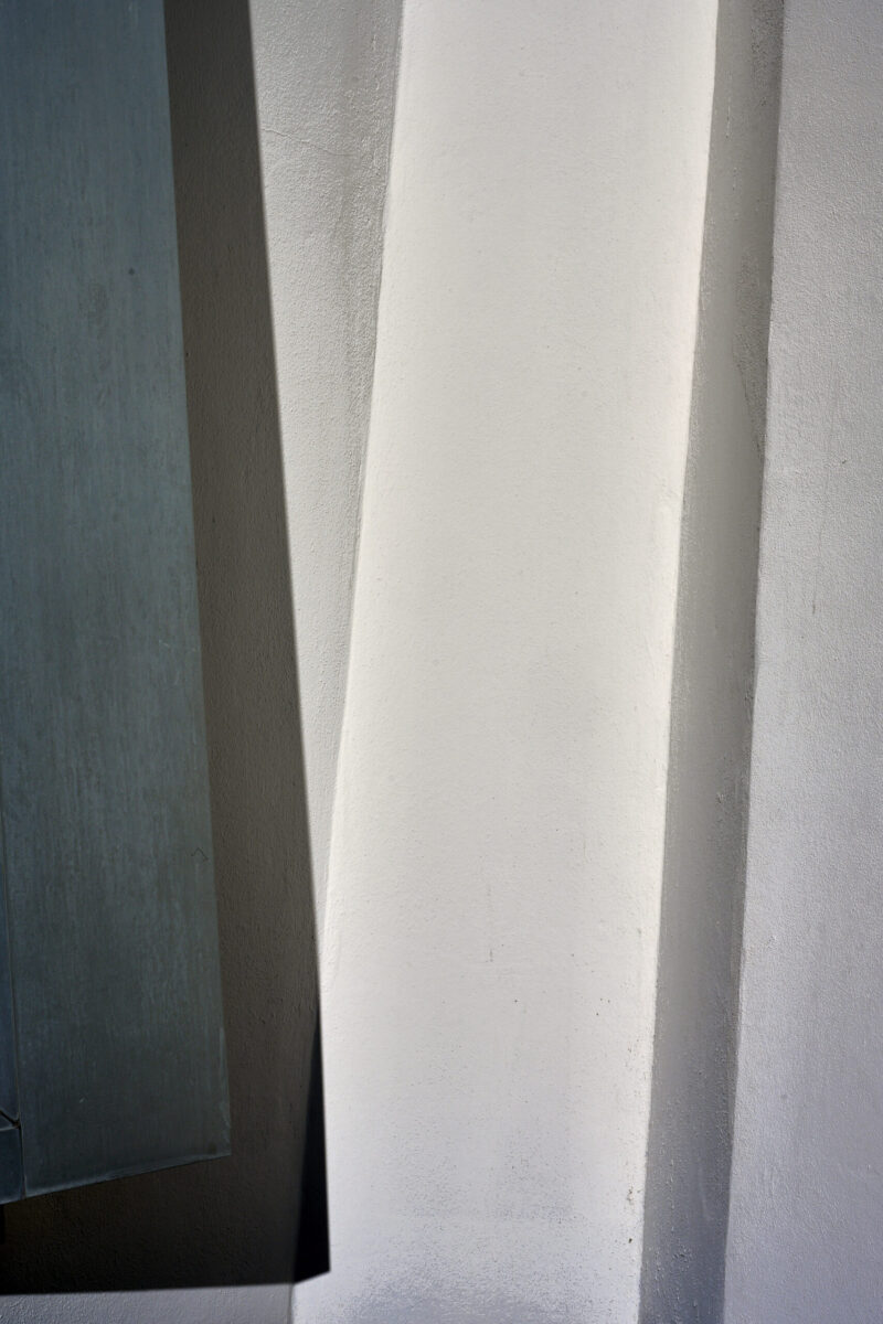 abstrakter minimalistischer Ausschnitt einer verschachtelten Hausfassade mit Schrägen und Horizontalen, Hochformat