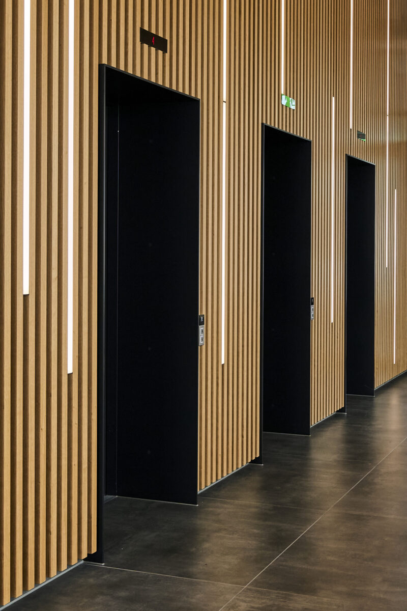 Architektur- und Interieurfotografie Düsseldorf Auxmoney, Eingangshalle mit Aufzügen, Wand mit Holzpaneelen und Lichtleisten