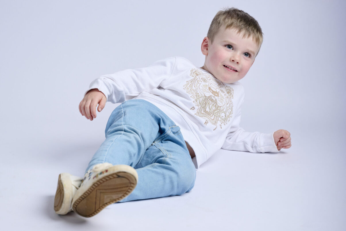Kindershooting, Lachender kleiner blonder Junge liegend