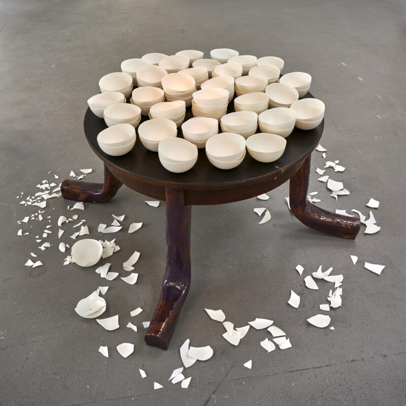 Eventfotografie Düsseldorf Ausstellung "72 Stunden - ein Zeitraum" von Corinna Bernshaus - Installation Tisch mit abgeknickten Beinen, weißen Porzellanschalen und Scherben auf dem Boden