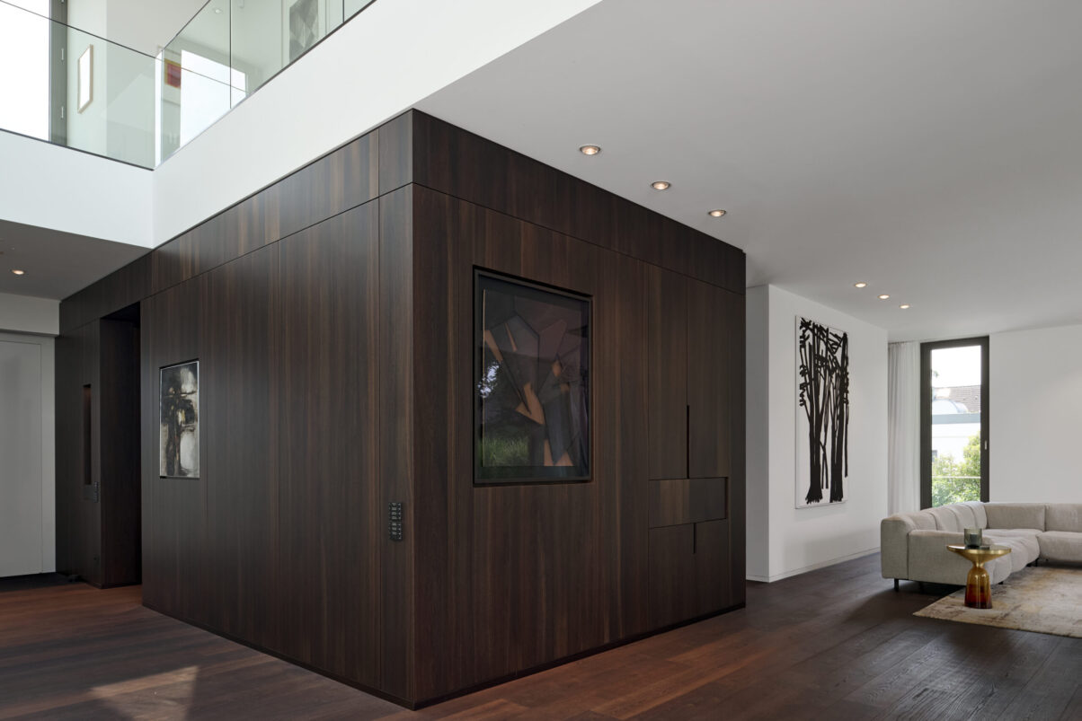 Architektur- und Interieurfotografie Düsseldorf MH Project Interieur, Wohnzimmer und Eingang mit Holz verbauter Ecke mit innenliegender Bar und integrierten Kunstwerken