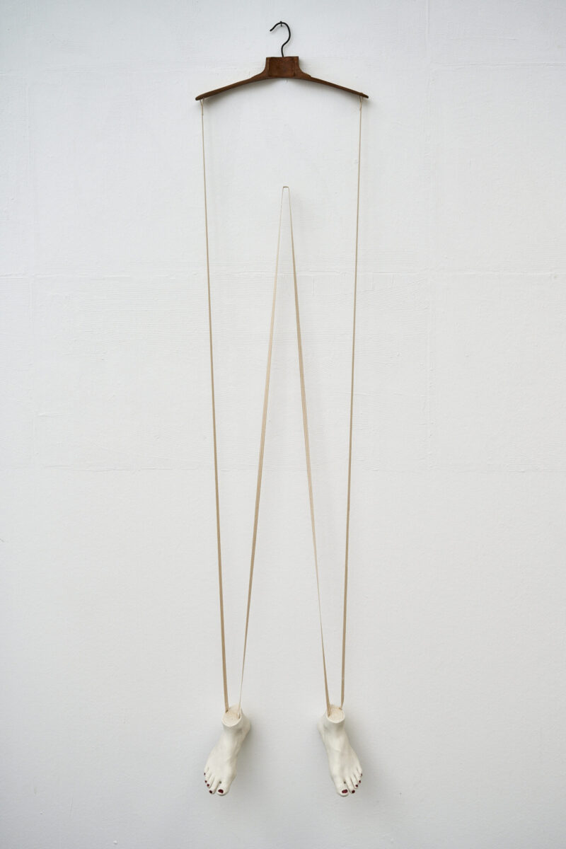 Eventfotografie Düsseldorf Ausstellung "72 Stunden - ein Zeitraum" von Corinna Bernshaus - weiße Wandskulptur aus Porzellan, Füße als Marionette hängend an einem Kleiderhaken