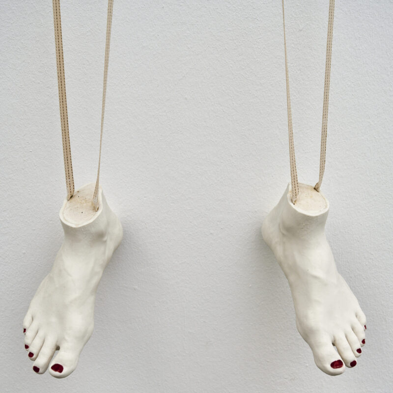 Eventfotografie Düsseldorf Ausstellung "72 Stunden - ein Zeitraum" von Corinna Bernshaus - Ausschnitt weiße Wandskulptur aus Porzellan, Füße als Marionette hängend an einem Kleiderhaken