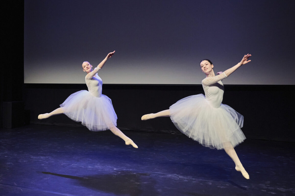 Eventfotografie Düsseldorf Ballettaufführung, klassische Choreographie, 2 Tänzerinnen im Sprung in klassischen, weißen "Schwanensee"-Kleidern