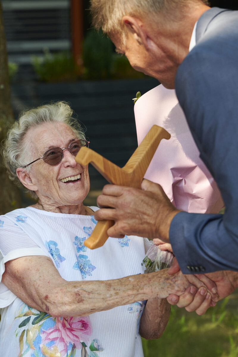Eventfotografie Düsseldorf Sonnenrad Festival 2023 - Übergabe eines Holzradschlägers von Bürgermeister Josef Hinkel an eine 100-jährige Dame