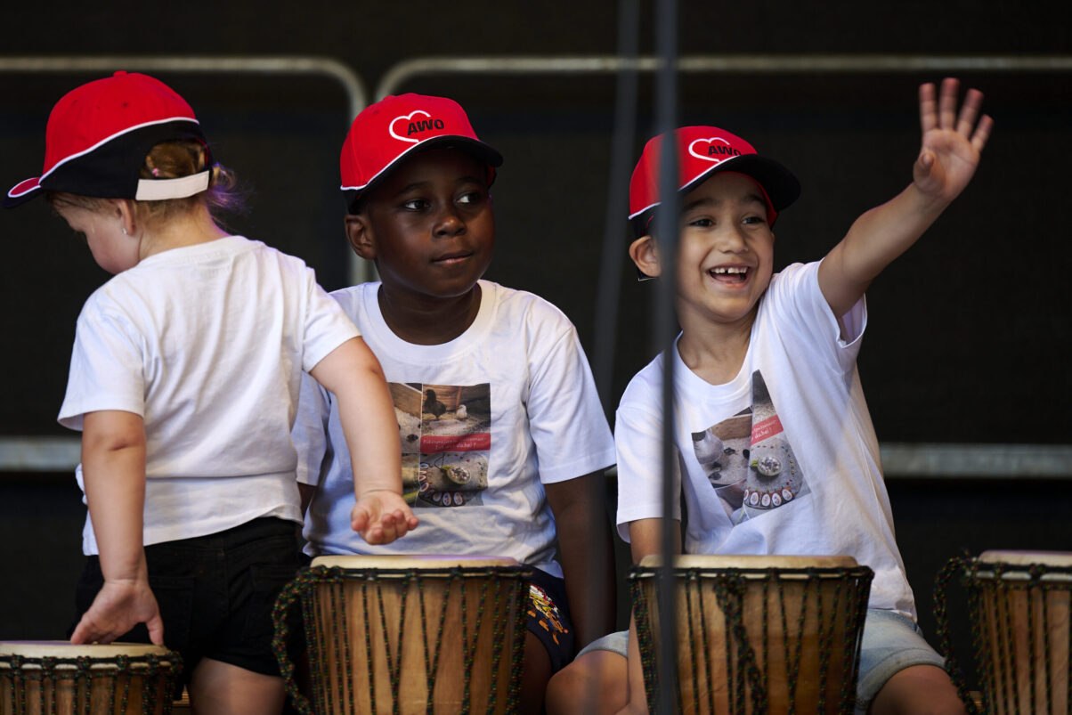 Eventfotografie Düsseldorf Sonnenrad Festival 2023 - drei kleine Jungs mit roten Kappen bei Trommelperformance