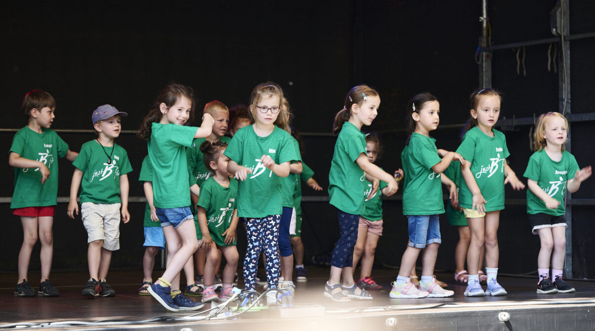 Eventfotografie Düsseldorf Sonnenrad Festival 2023 - Kindertanzgruppe in grünen T-Shirts