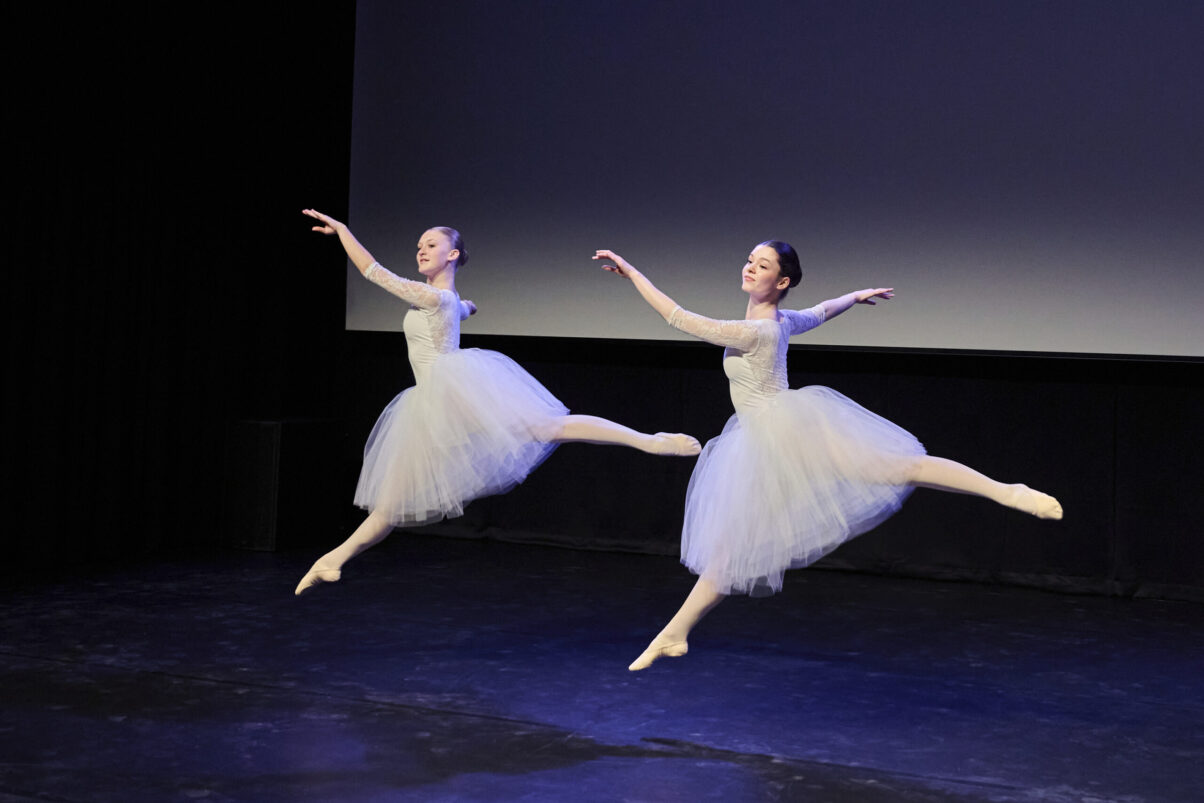 Eventfotografie Düsseldorf Ballettaufführung, klassische Choreographie, 2 Tänzerinnen im Sprung in klassischen, weißen "Schwanensee"-Kleidern