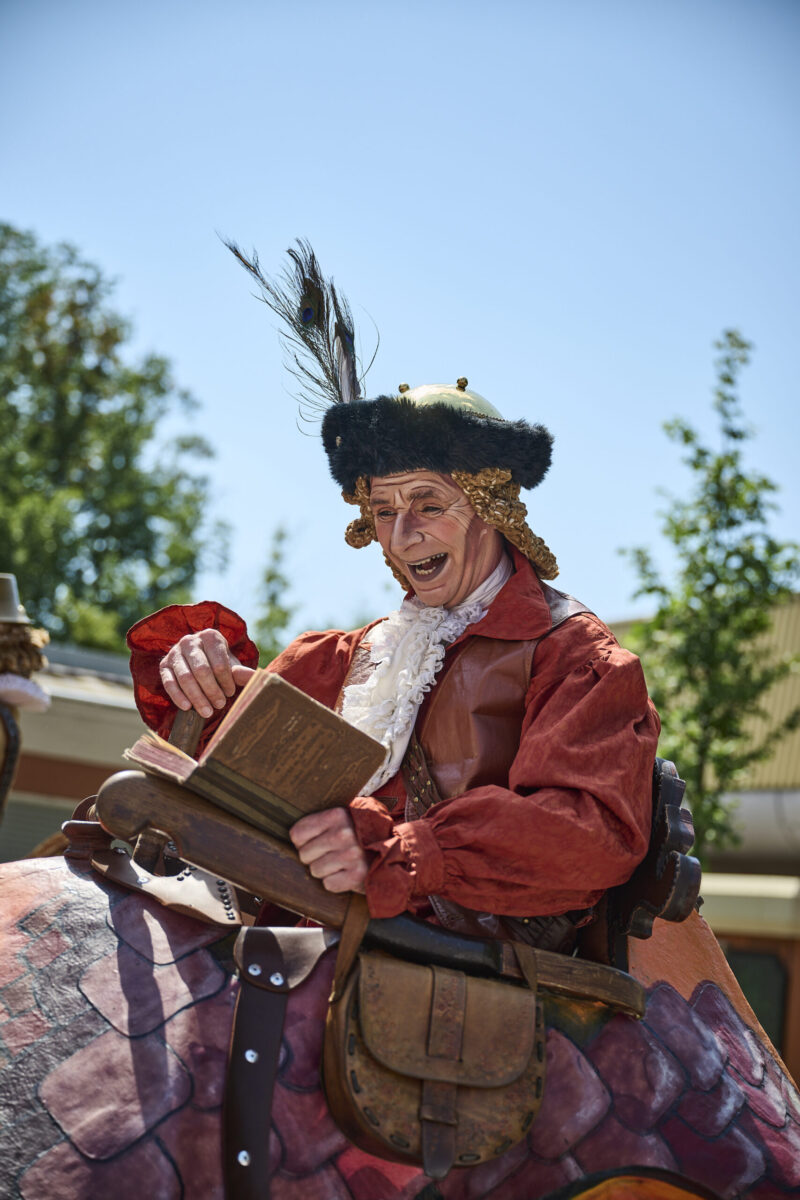 Eventfotografie Düsseldorf Sonnenrad Festival 2023 - Schausteller in barocker Kleidung mit Federhut und Buch in der Hand