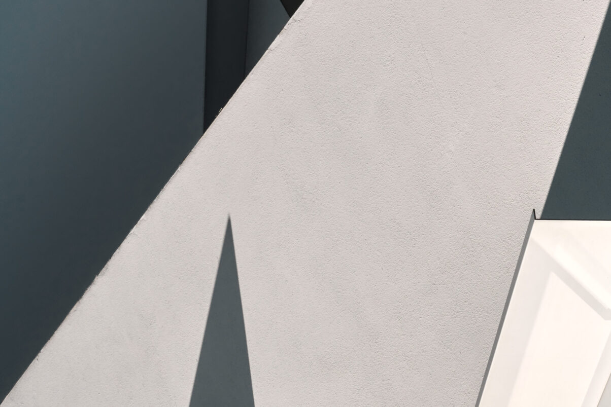 abstrakter minimalistischer Ausschnitt einer Hausfassade mit Dreiecken durch Schatten hervorgerufen, Querformat