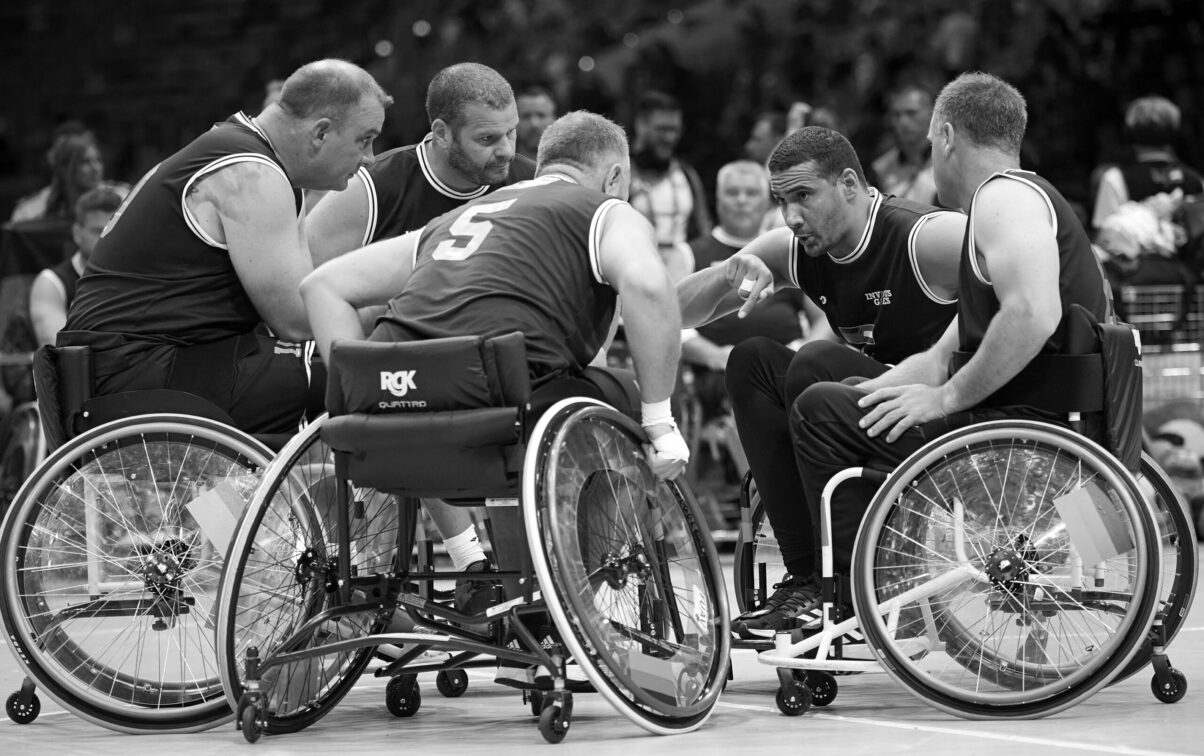 Ausstellung Spirit of Invictus Games Düsseldorf 2023 Rollstuhl Basketballspieler bei der Teambesprechung