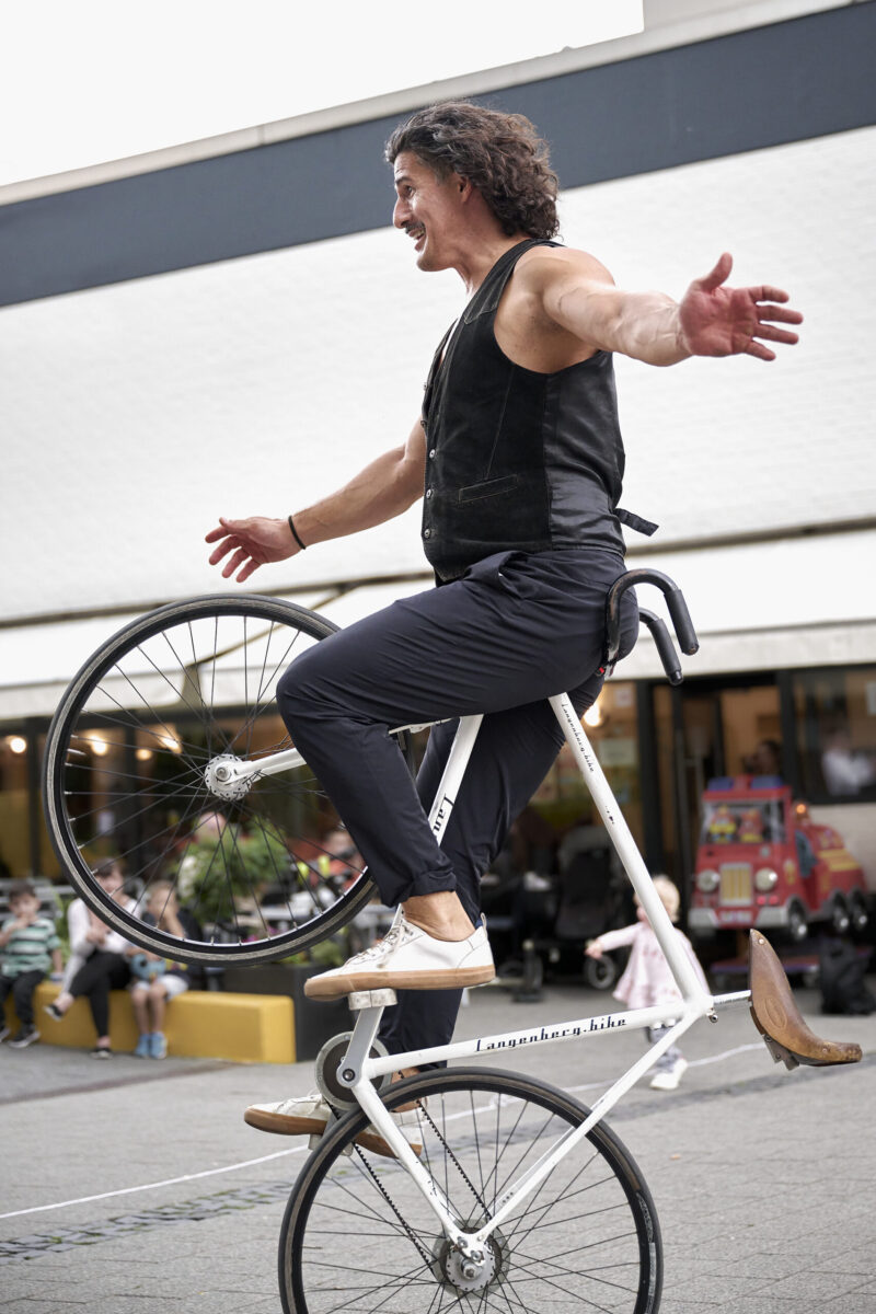 Pop up Artistik Festival, Artist auf einem Fahrrad, nur auf dem Hinterrad fahrend