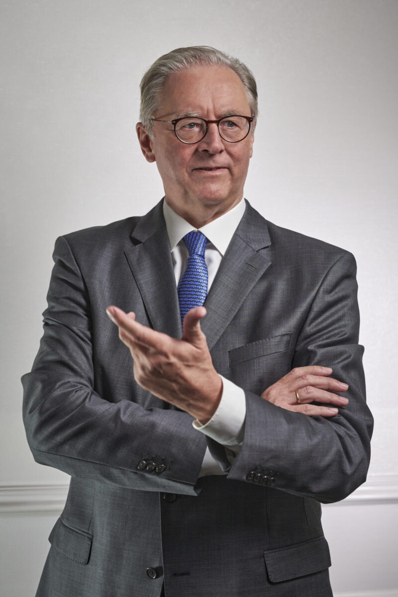 Peoplefotografie Düsseldorf, Business Porträts Düsseldorf Business Porträt eines Vorstandsmitglieds mit offener Handhaltung im dunkelgrauen Anzug