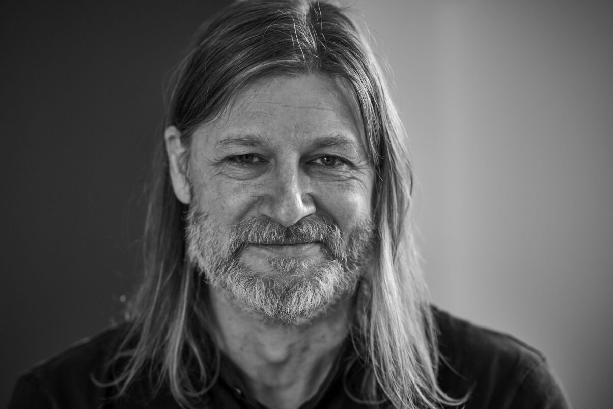 Mann mit langen Haaren und coolem und lächelndem Blick, Schwarzweißfoto