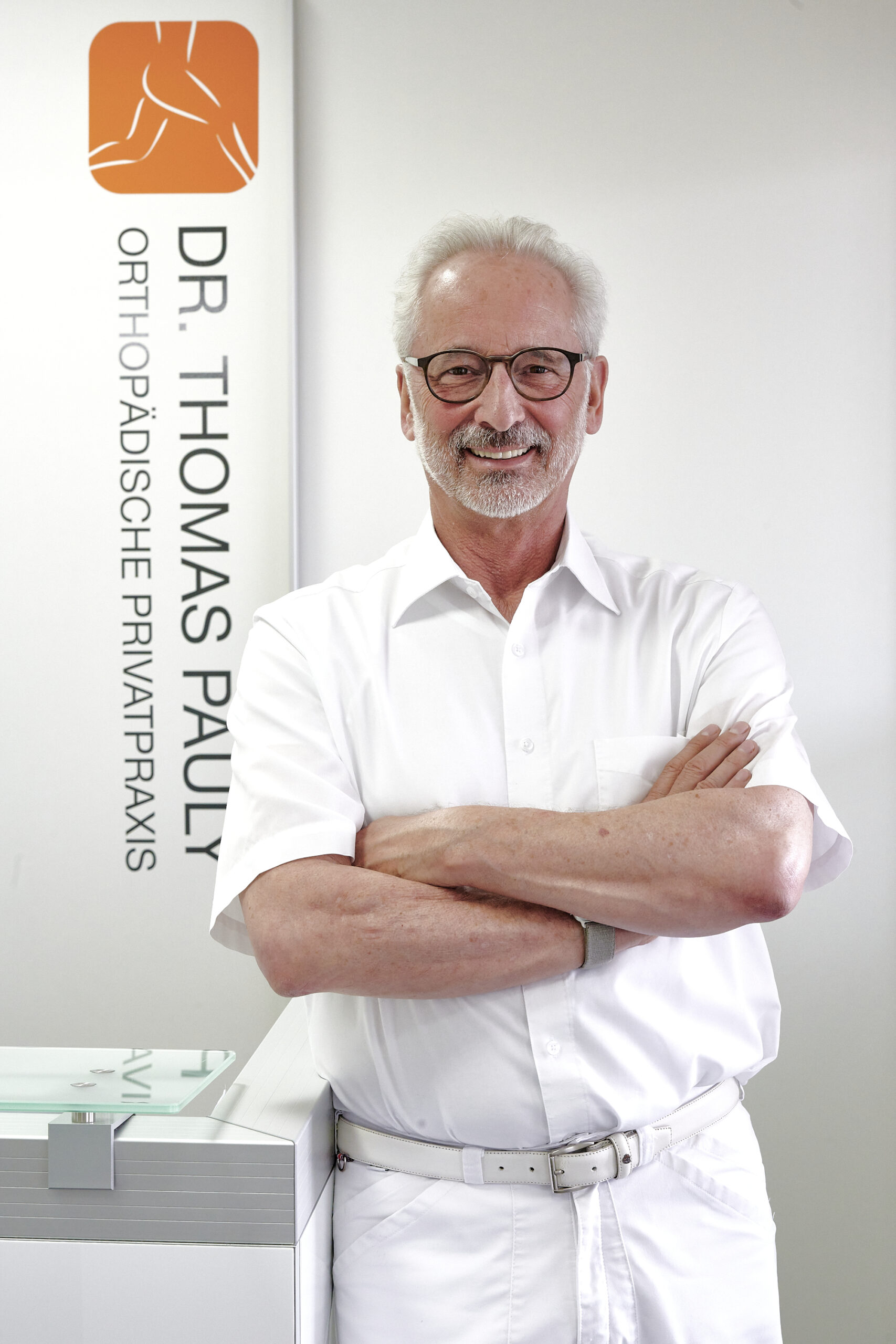 Peoplefotografie Düsseldorf, Business Porträts Düsseldorf Halbporträt eines lachenden Arztes am Empfangstresen seiner Praxis