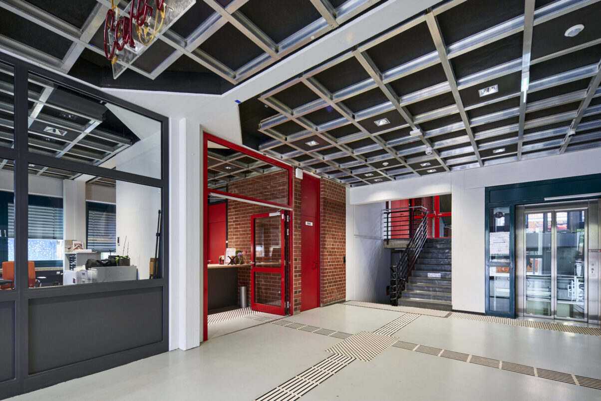 Architektur- und Interieurfotografie Düsseldorf Kulturhaus Süd, Eingangsbereich mit roten Details und Stahlkonstruktionsdecke