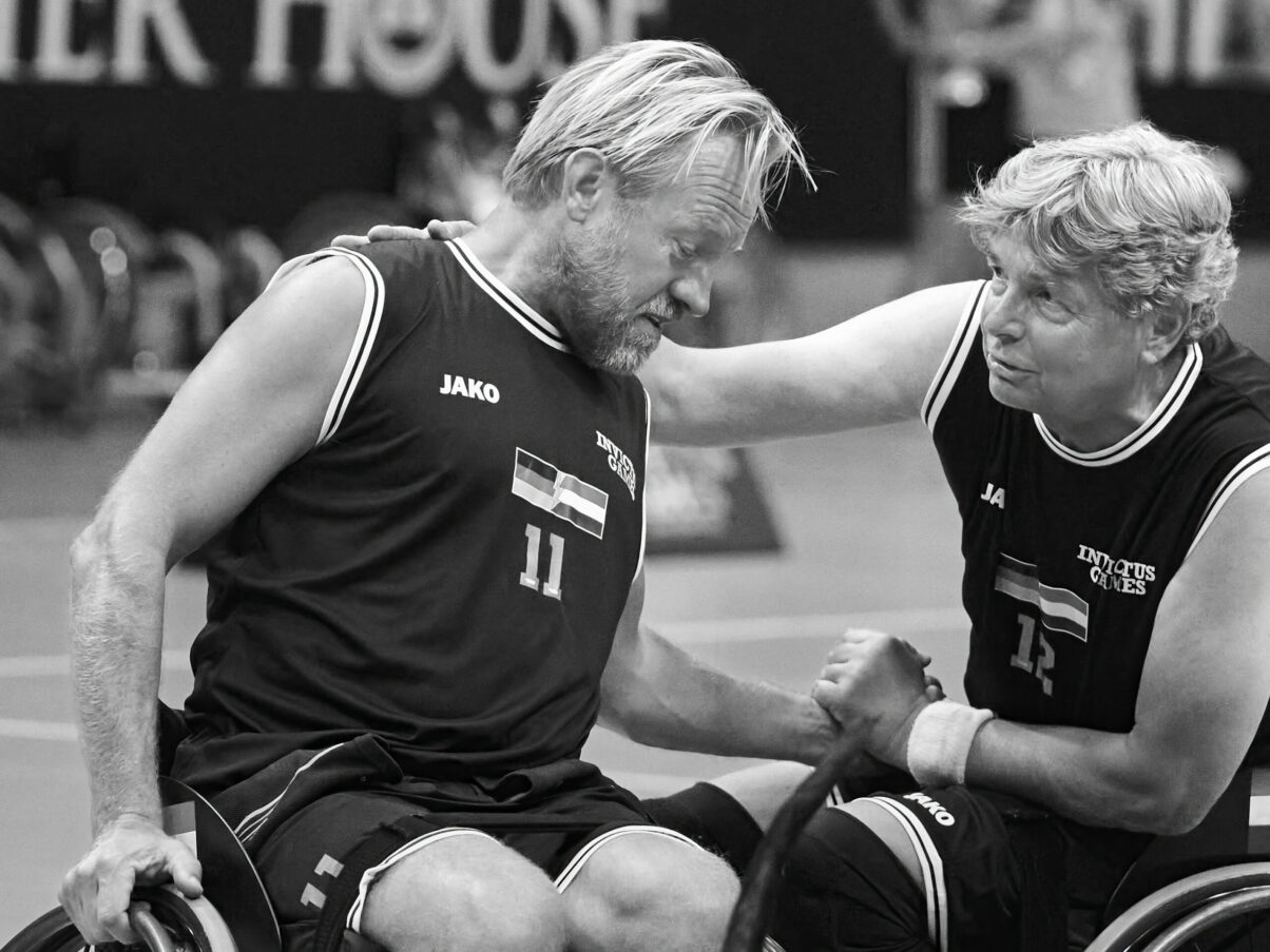 Ausstellung Spirit of Invictus Games Düsseldorf 2023 Anschnitt von zwei Baskettballspielern im Rollstuhl, einer spendet dem anderen Trost
