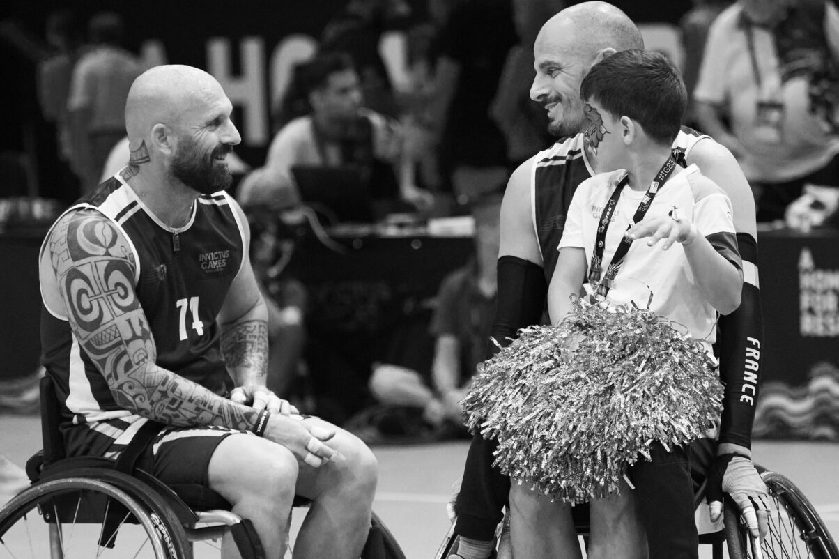 Ausstellung Spirit of Invictus Games Düsseldorf 2023 zwei Baskettballspieler im Rollstuhl, einer mit Sohn, lachend, erzählend