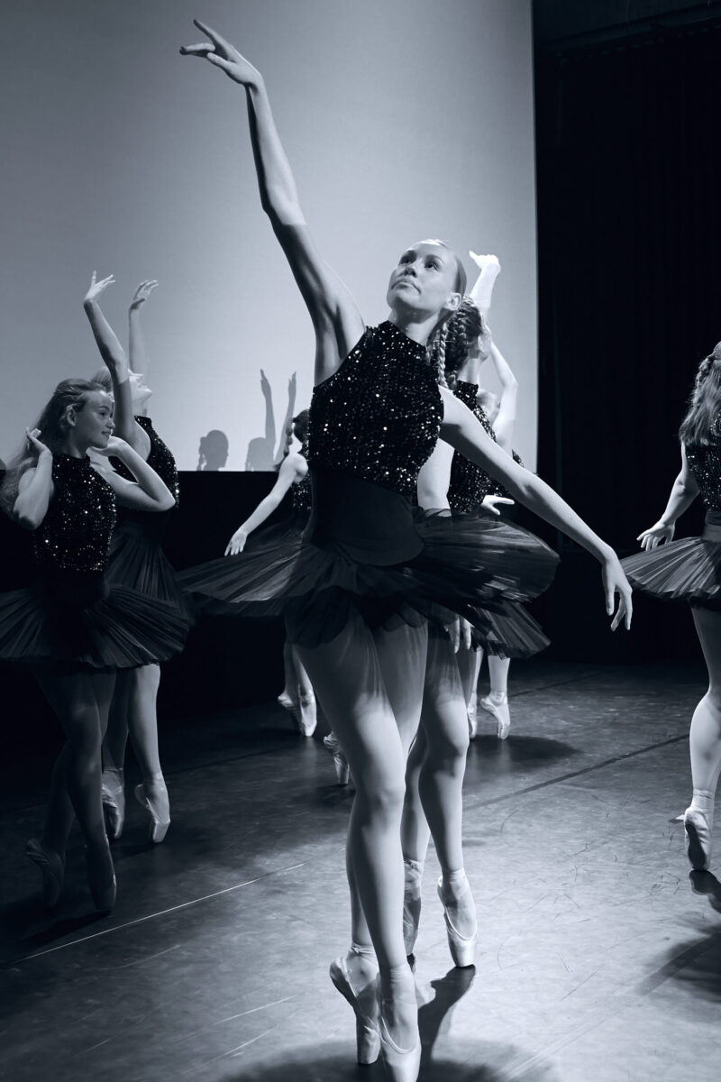 Eventfotografie Düsseldorf Ballettaufführung, klassische Choreographie, Tänzerinnen auf Spitzen posierend in klassischen, schwarzen "Schwanensee"-Kleidern mit Paillettenoberteil