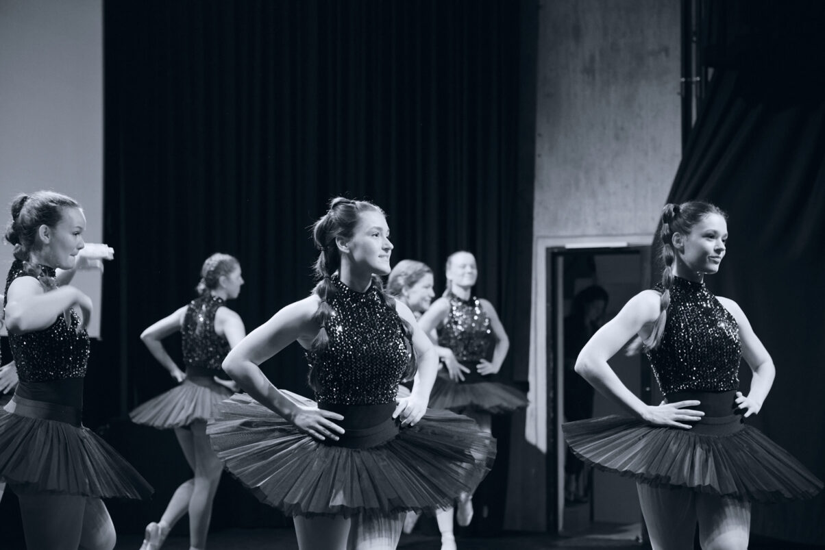 Eventfotografie Düsseldorf Ballettaufführung, klassische Choreographie, Tänzerinnen auf Spitzen posierend in klassischen, schwarzen "Schwanensee"-Kleidern mit Paillettenoberteil