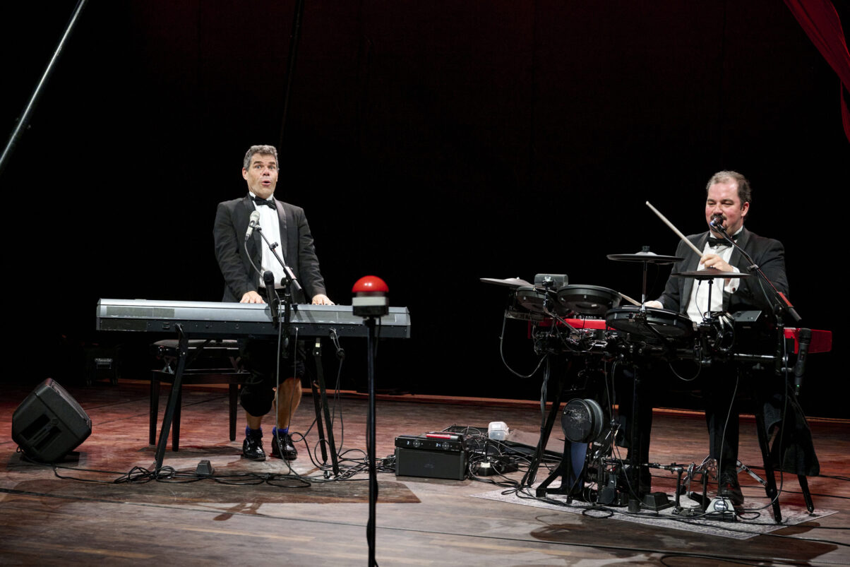 Eröffnungsgala Kulturhaus Süd - Comedians im schwarzen Smoking auf der Bühne am Keyboard und am Schlagzeug