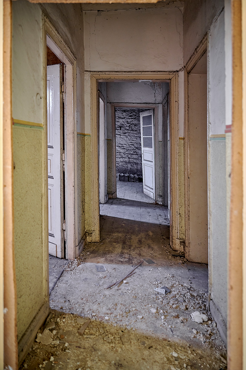 Architektur- und Interieurfotografie Düsseldorf SKFM Sanierung Altbau, Durchgang mit mehreren Zimmereingängen, verratzten Wänden und aufgebrochenem Boden