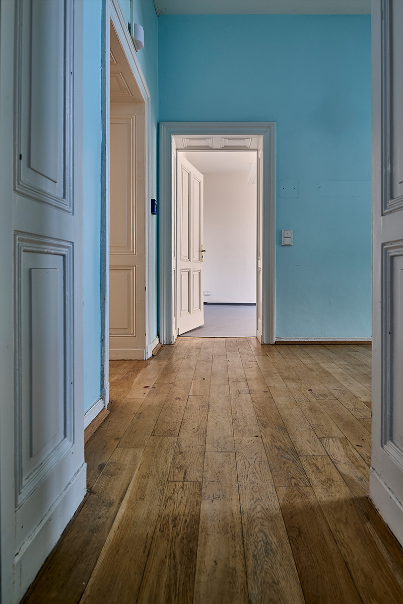 Architektur- und Interieurfotografie Düsseldorf SKFM Sanierung Altbau, Zimmerflucht mit altem Parkett, weißen Kassettentüren und mittelblauen Wänden