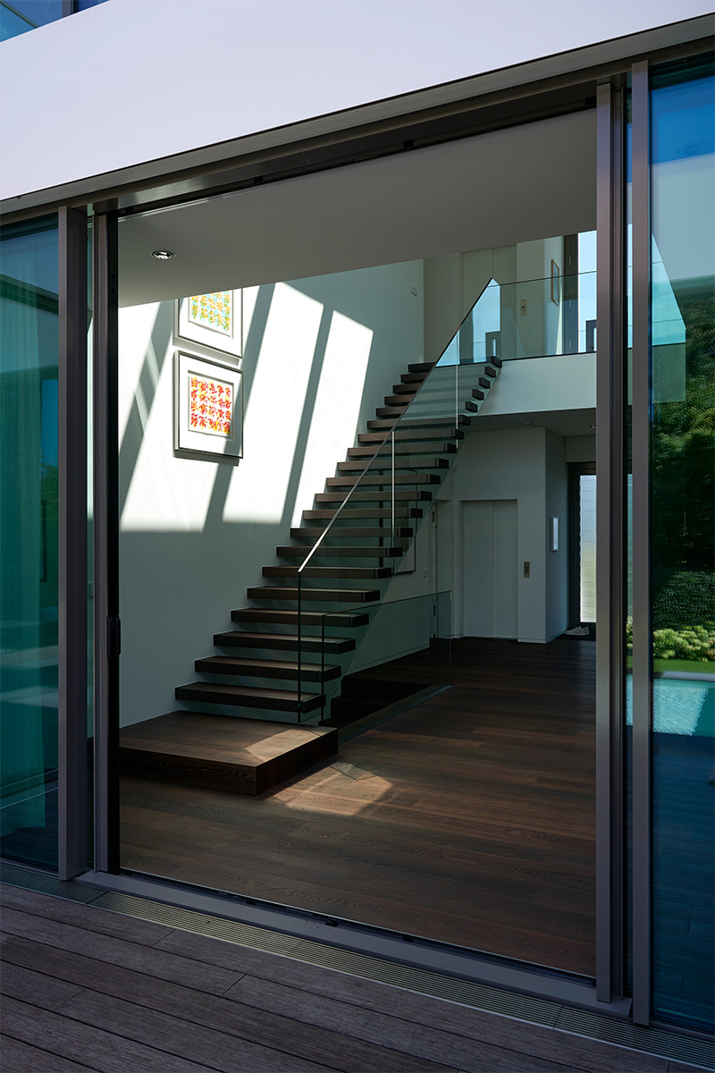 Architektur- und Interieurfotografie Düsseldorf MH Project, Durchsicht von der Terrasse ins Haus mit der Eingangshalle und Treppe nach oben