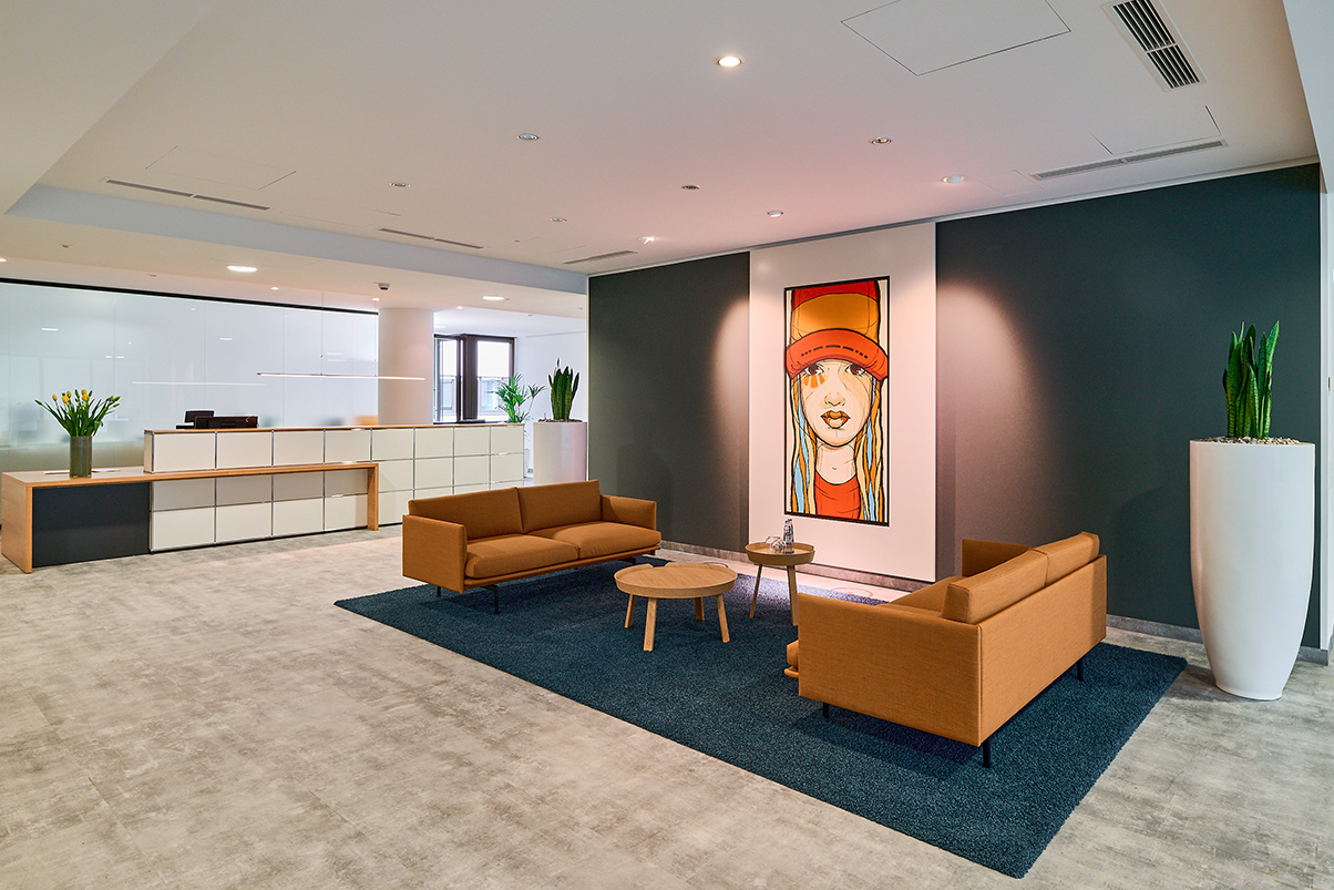 Projekt Büro Kö 60c in Düsseldorf, einladender Eingangsbereich mit moderner Sitzgarnitur, großem Bild und Empfangstresen im Hintergrund
